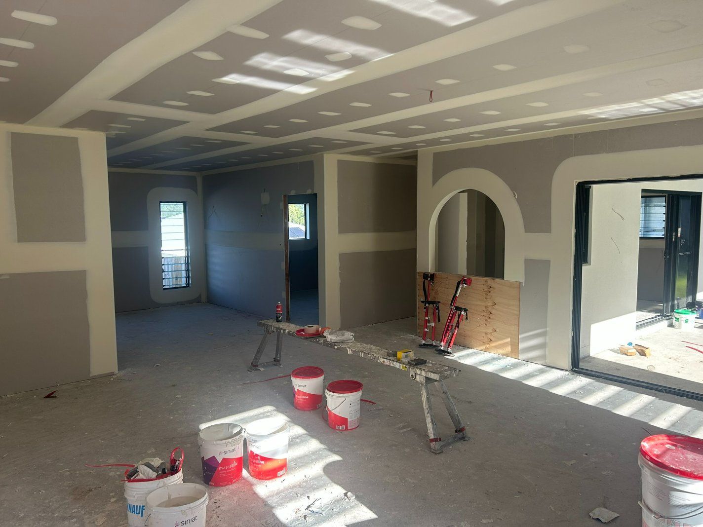 An Empty Room With Buckets of Paint on the Floor — Hams Plastering in Cannonvale, QLD