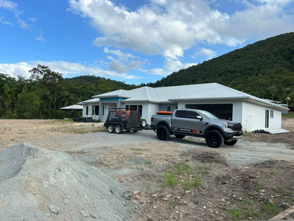 A Truck is Parked in Front of a House With Mountains — Hams Plastering in Cannonvale, QLD