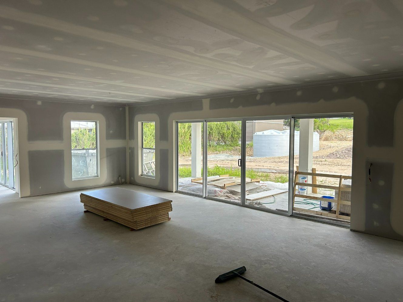 An Empty Room With a Table and a Broom in It — Hams Plastering in Cannonvale, QLD