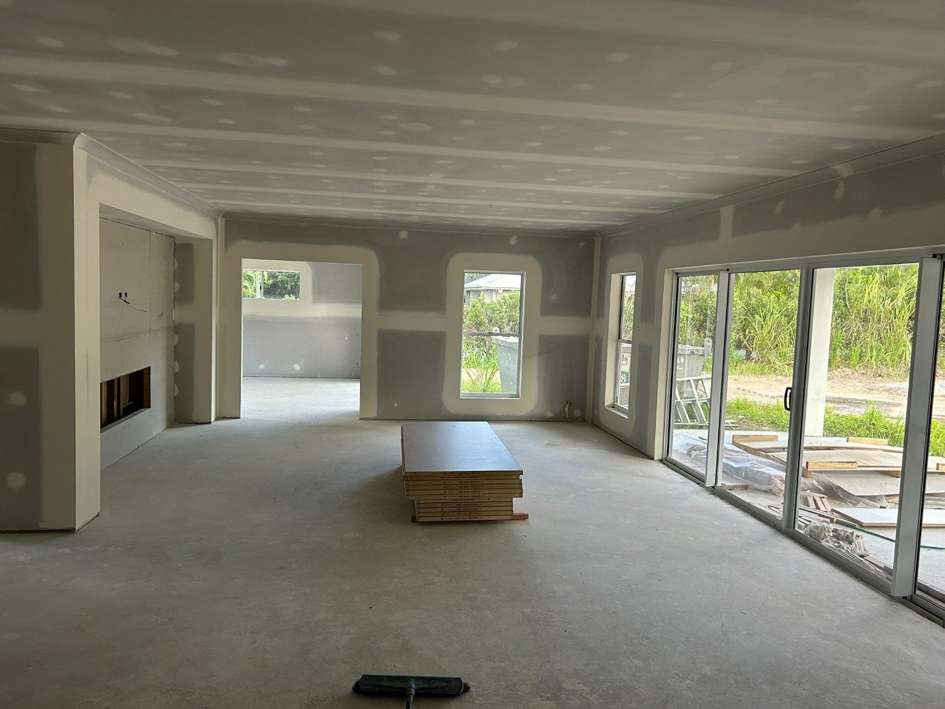 A Large Empty Room With a Table in the Middle of It — Hams Plastering in Cannonvale, QLD