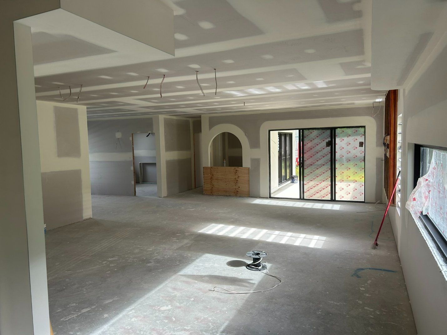 An Empty Room With a Sliding Glass Door and a Window — Hams Plastering in Cannonvale, QLD