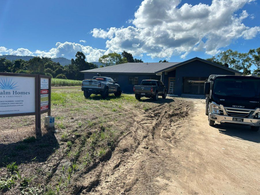 Two Trucks Are Parked in Front of a House on a Dirt Road — Hams Plastering in Cannonvale, QLD