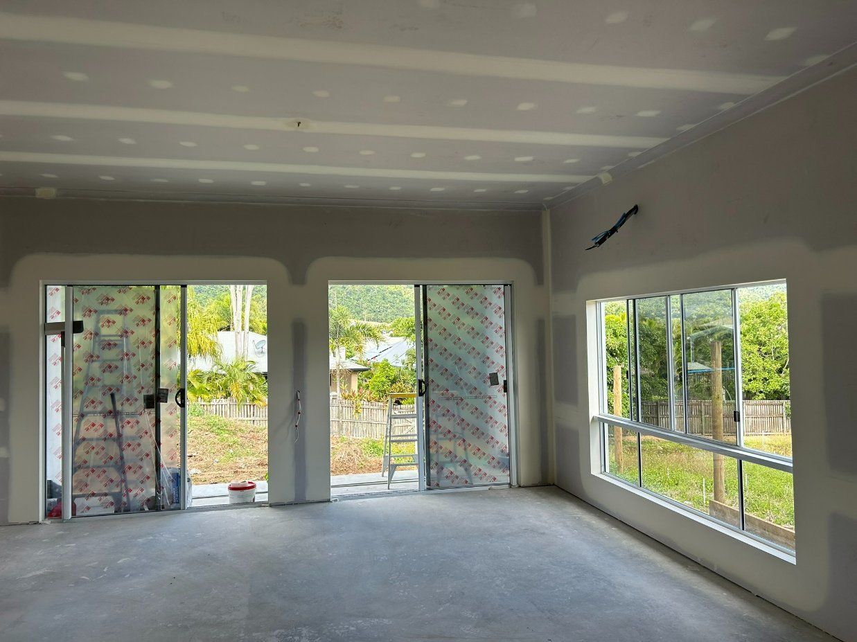A Large Empty Room With Windows — Hams Plastering in Cannonvale, QLD