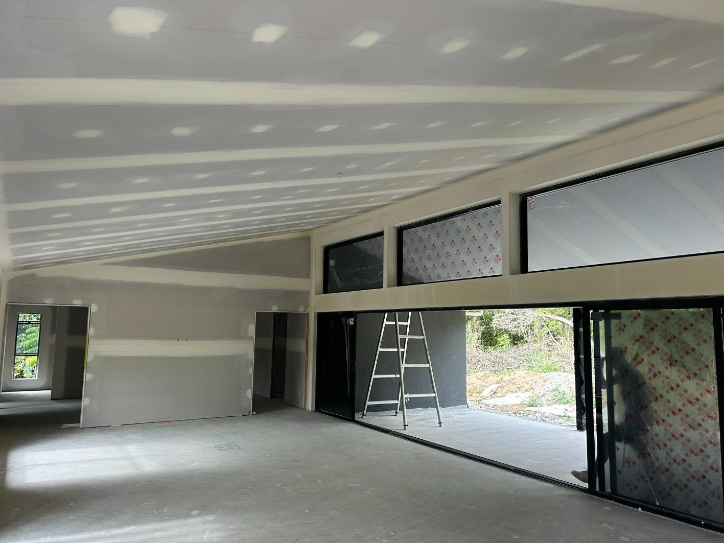 A Large Empty Room With a Ladder — Hams Plastering in Cannonvale, QLD