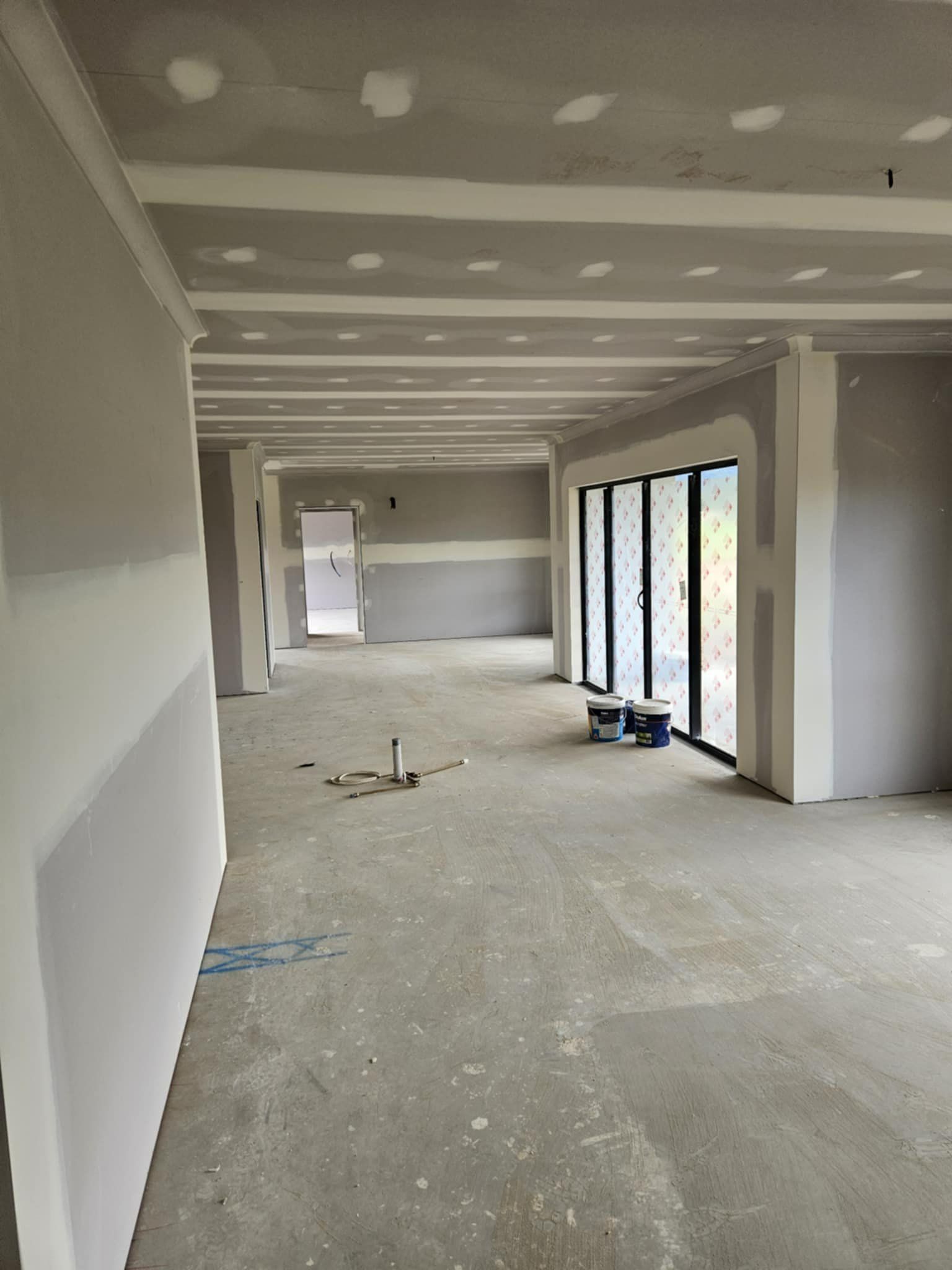A Large Empty Room With a  Plastered Dry Wall — Hams Plastering in Cannonvale, QLD