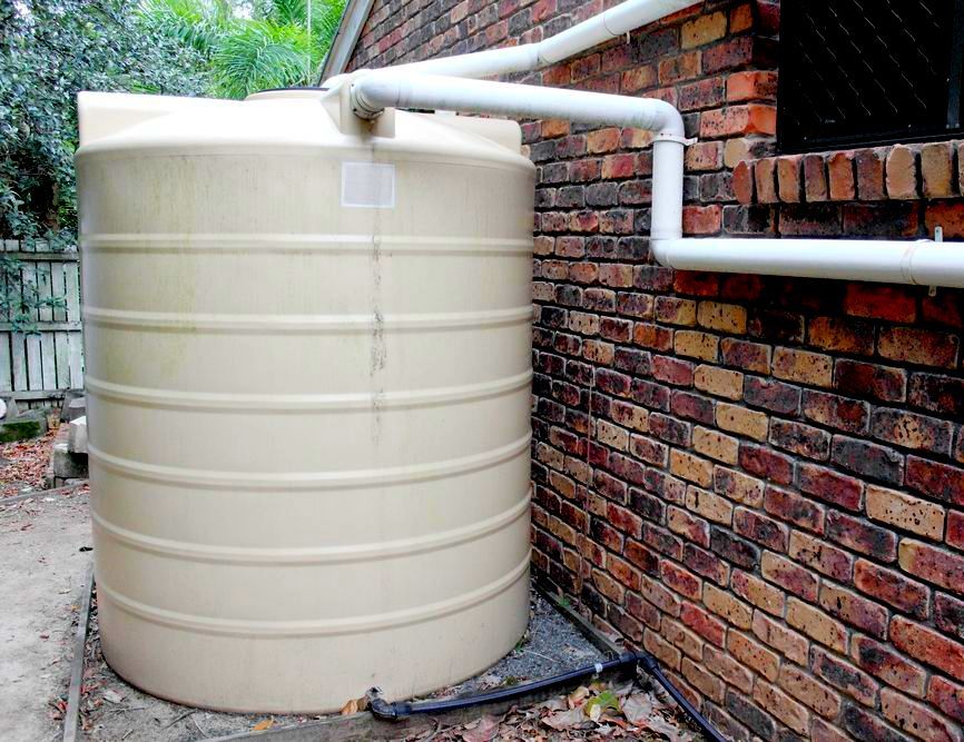 A Large Water Tank Is Attached To The Side Of A Brick Building — Ram Star Plastics In Winnellie, NT
