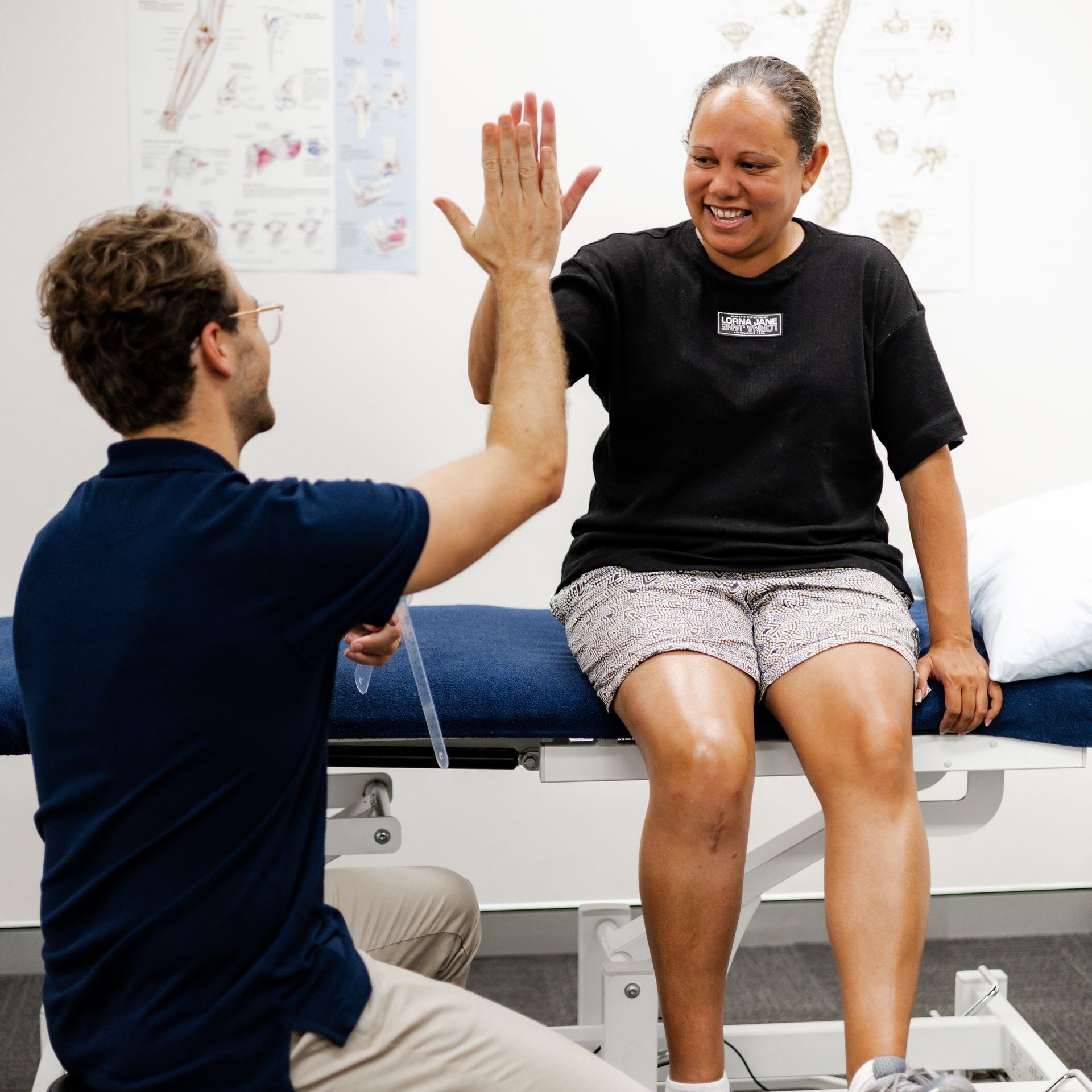 A man gives a woman a high five while she sits on a bench