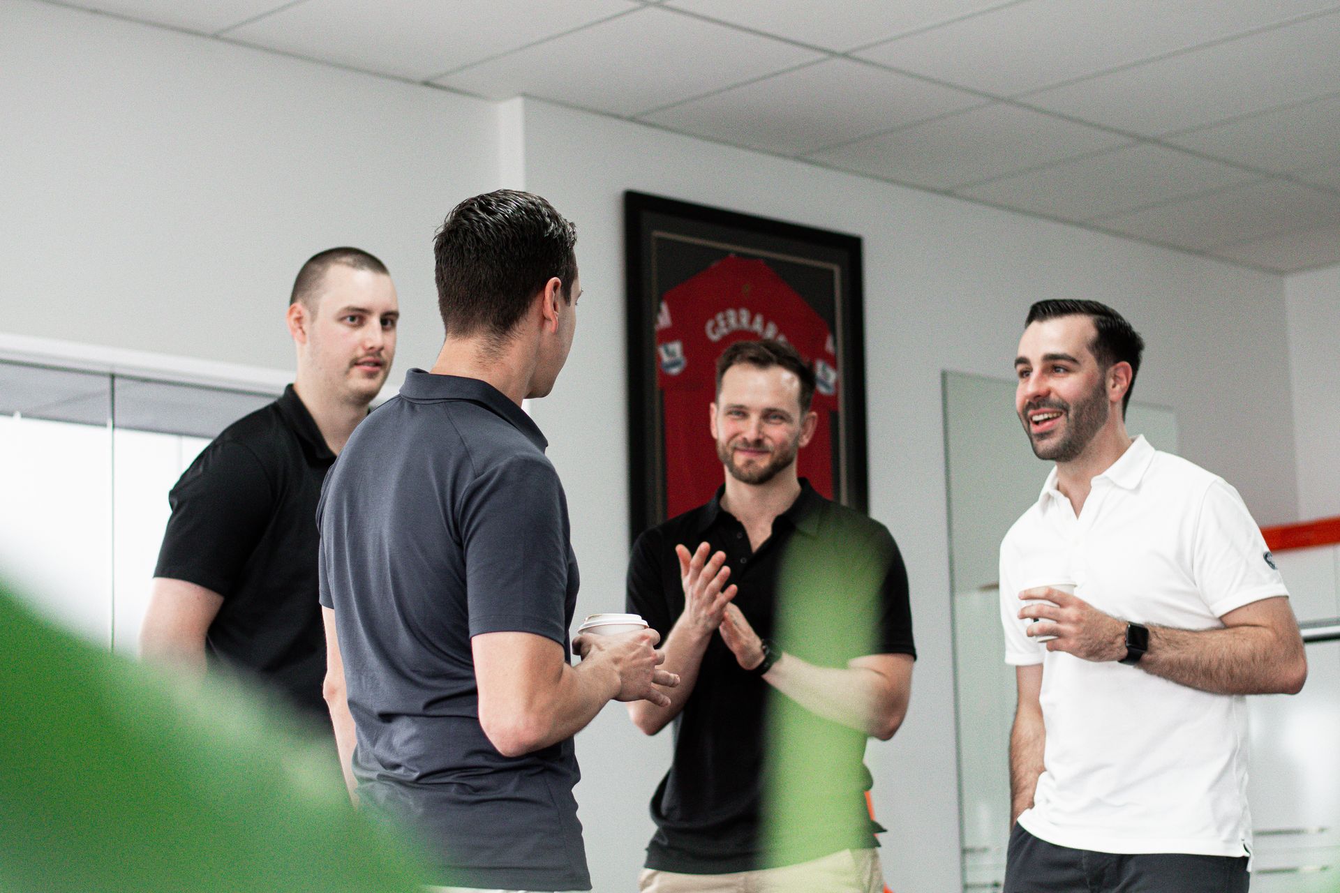 A group of men are standing in a room talking to each other.