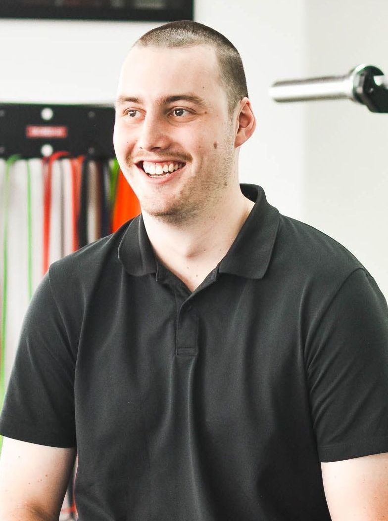 A man wearing a black polo shirt is smiling