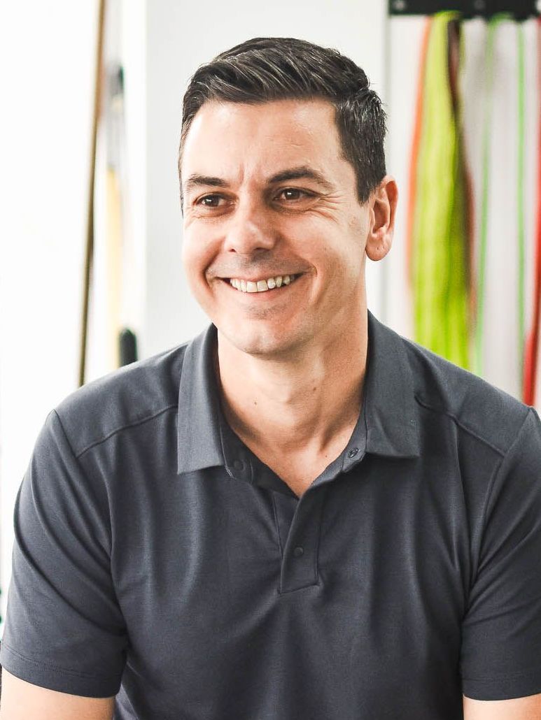 A man wearing a grey polo shirt is smiling for the camera.