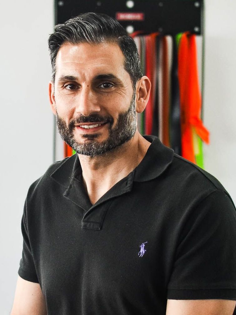 A man with a beard is wearing a black polo shirt.