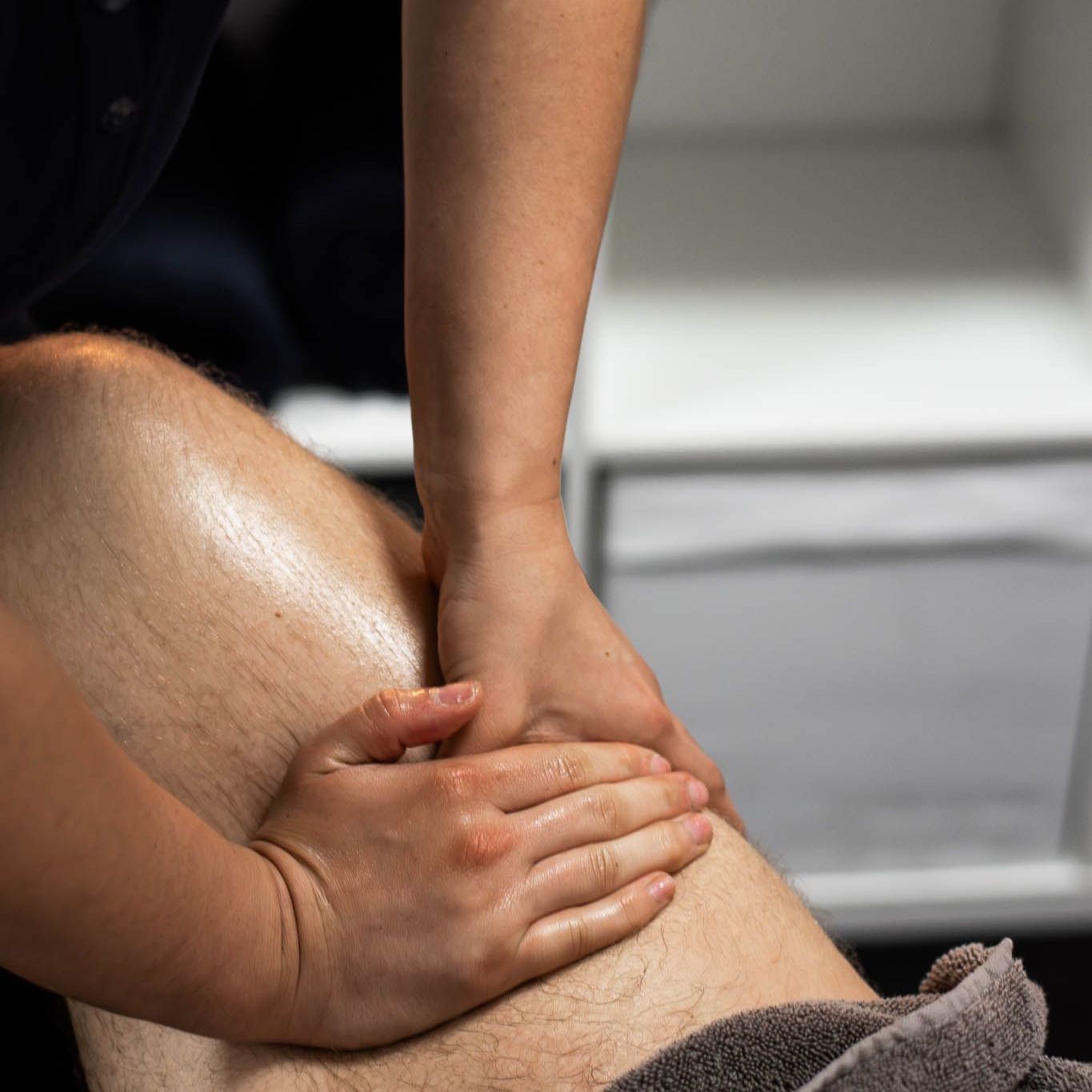 A woman is giving a man a massage on his leg.