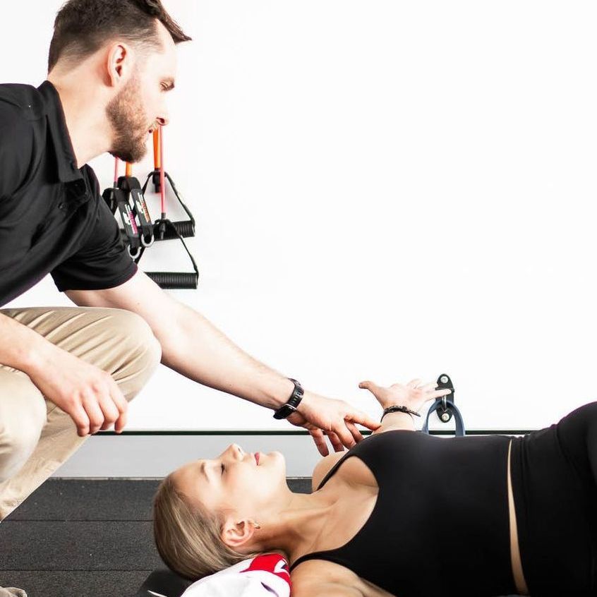 A man is kneeling down next to a woman laying on the floor