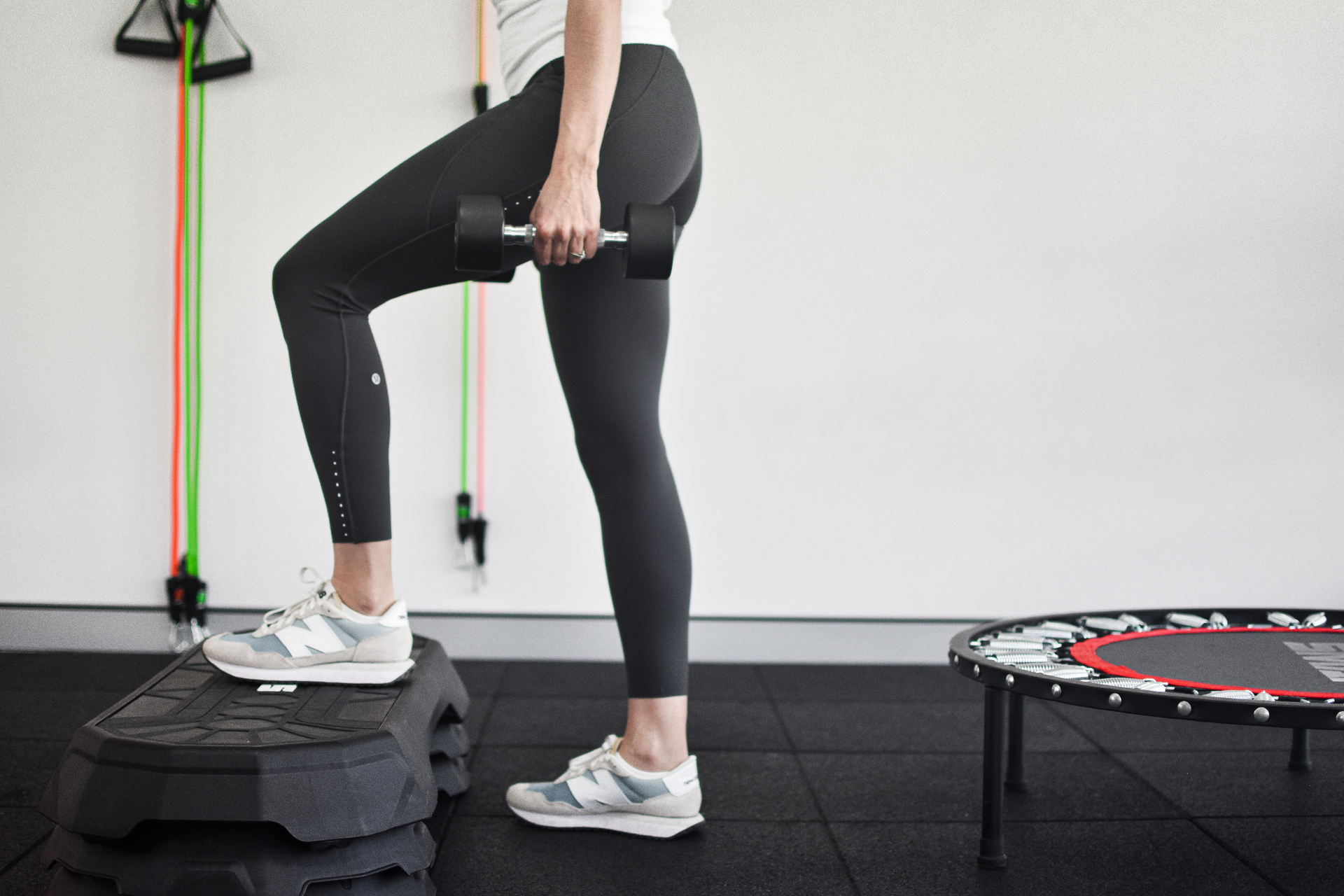Woman doing step-up exercise with a dumbbell in a gym.