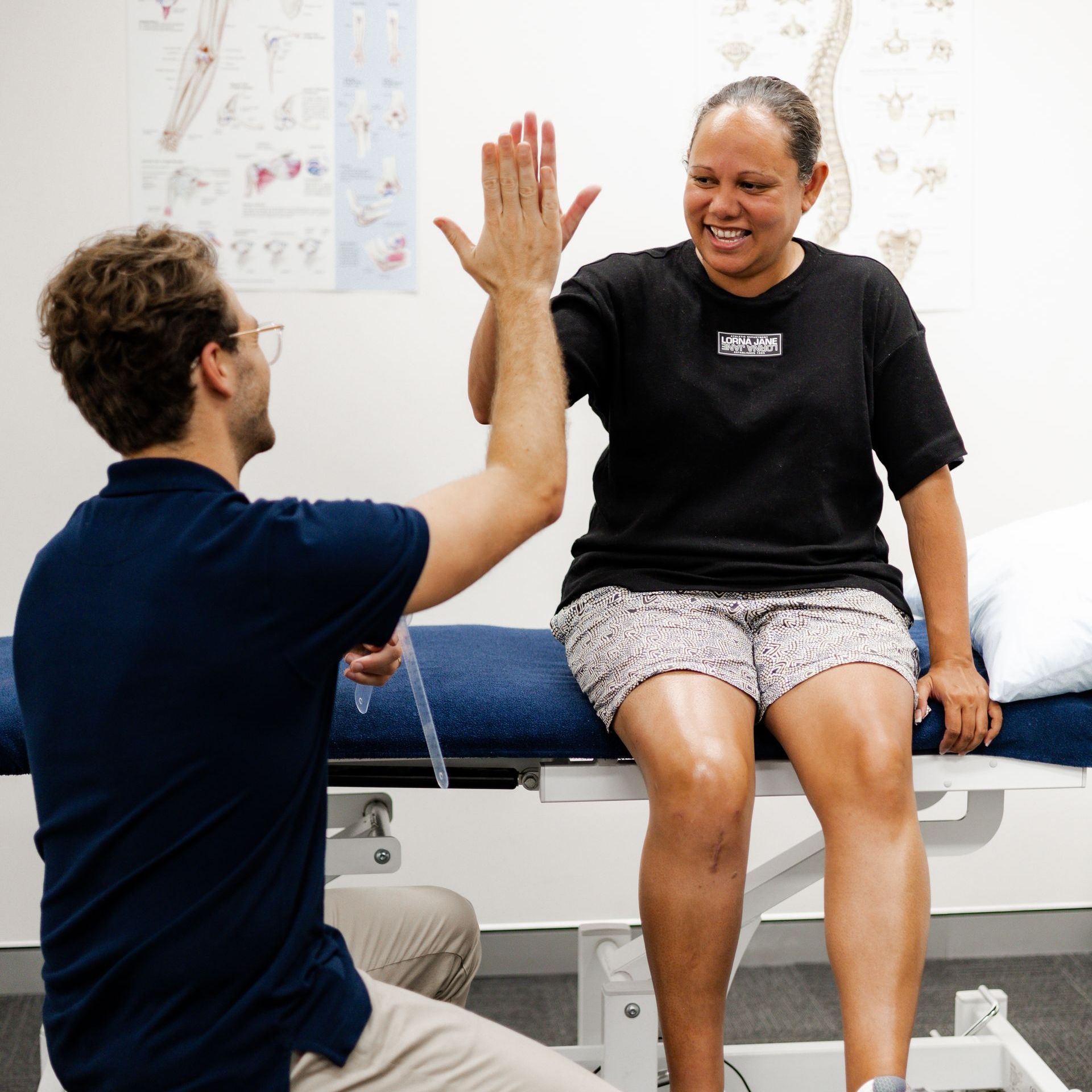 Man and woman giving each other a high five in a medical setting. They are smiling.