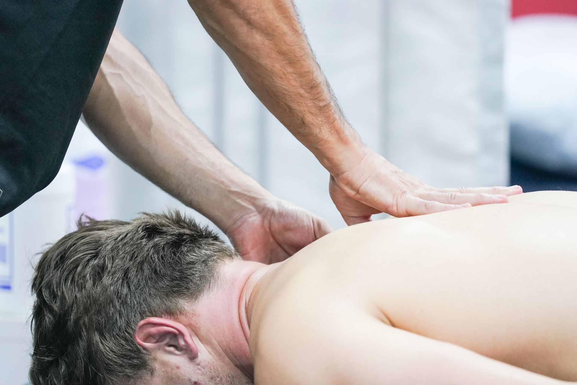 A man is laying on his back getting a massage from another man.