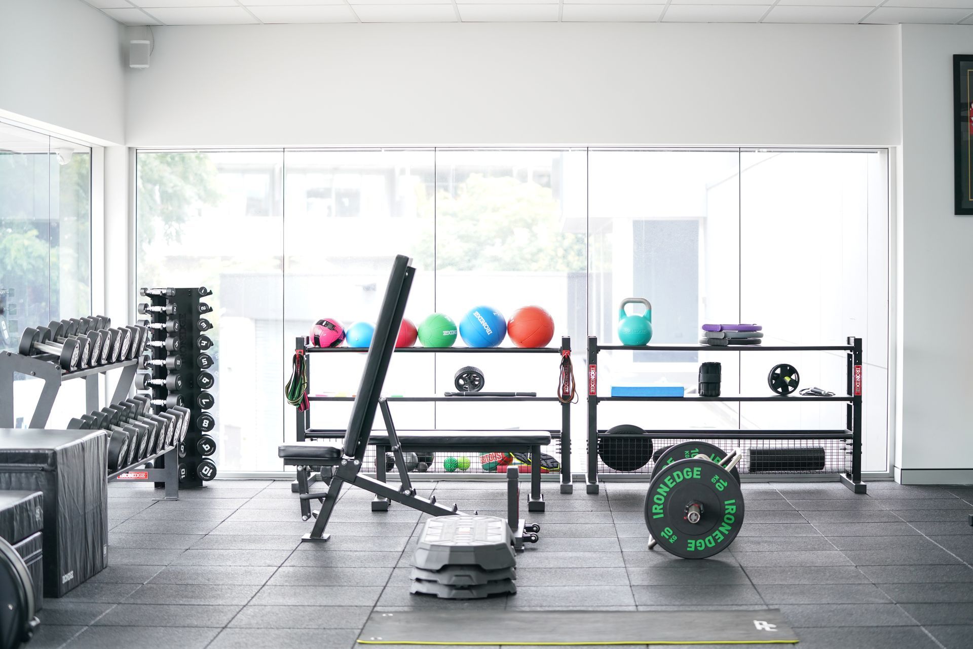 A gym filled with lots of exercise equipment and a bench.