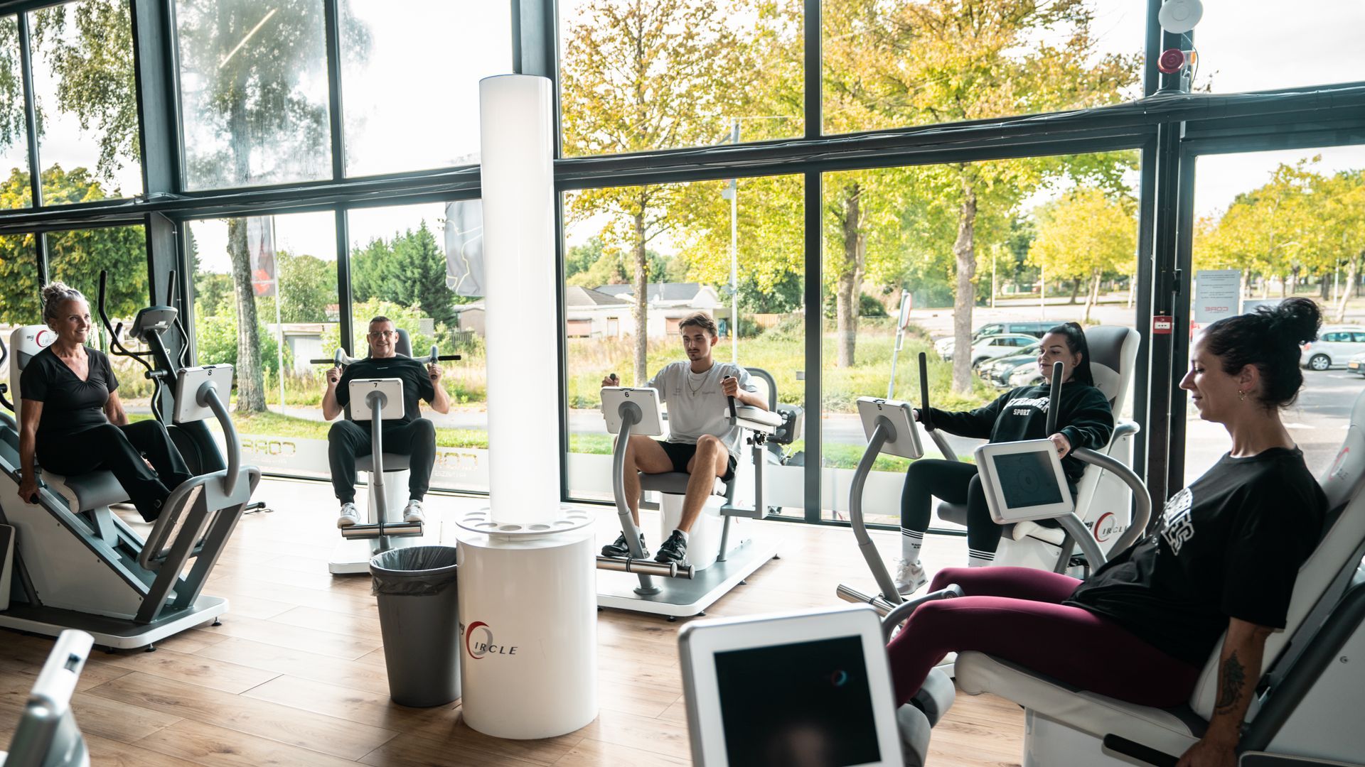 Een vrouw doet dumbbell row in de sportschool. Ze staat in plankpositie, met een geconcentreerde expressie.