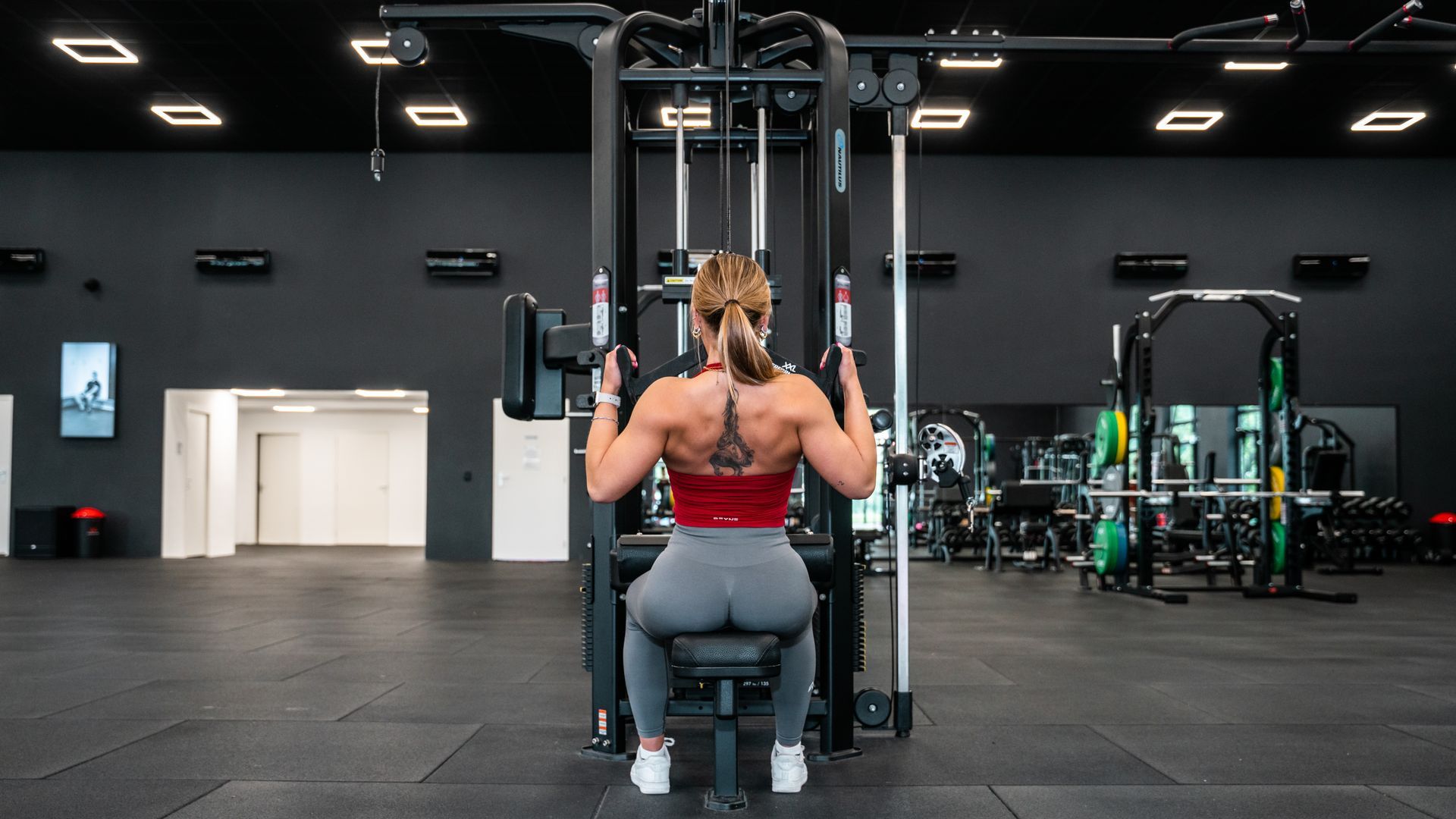 Een vrouw en een man trainen met battle ropes in een donkere sportschool.