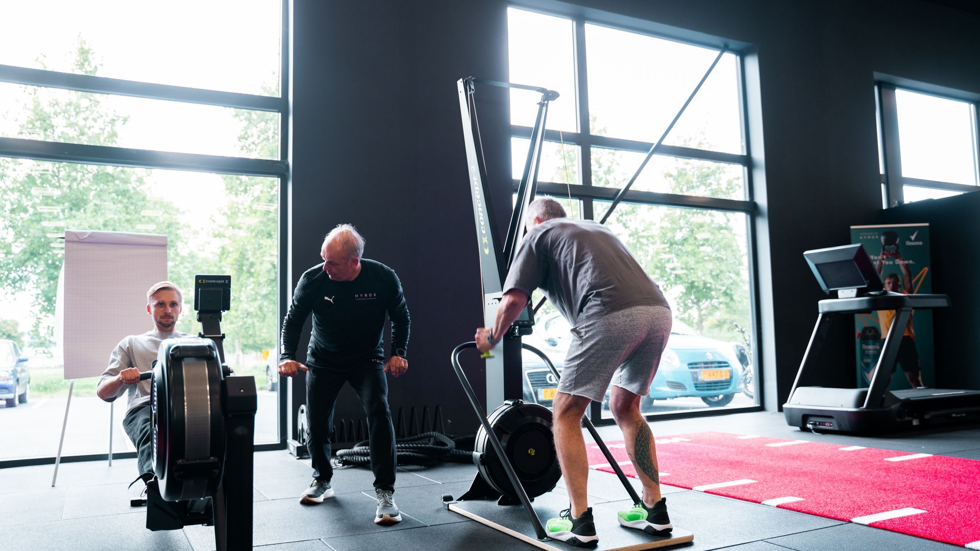 Mensen oefenen op matten met oefenballen in een sportschool en doen een core-oefening.