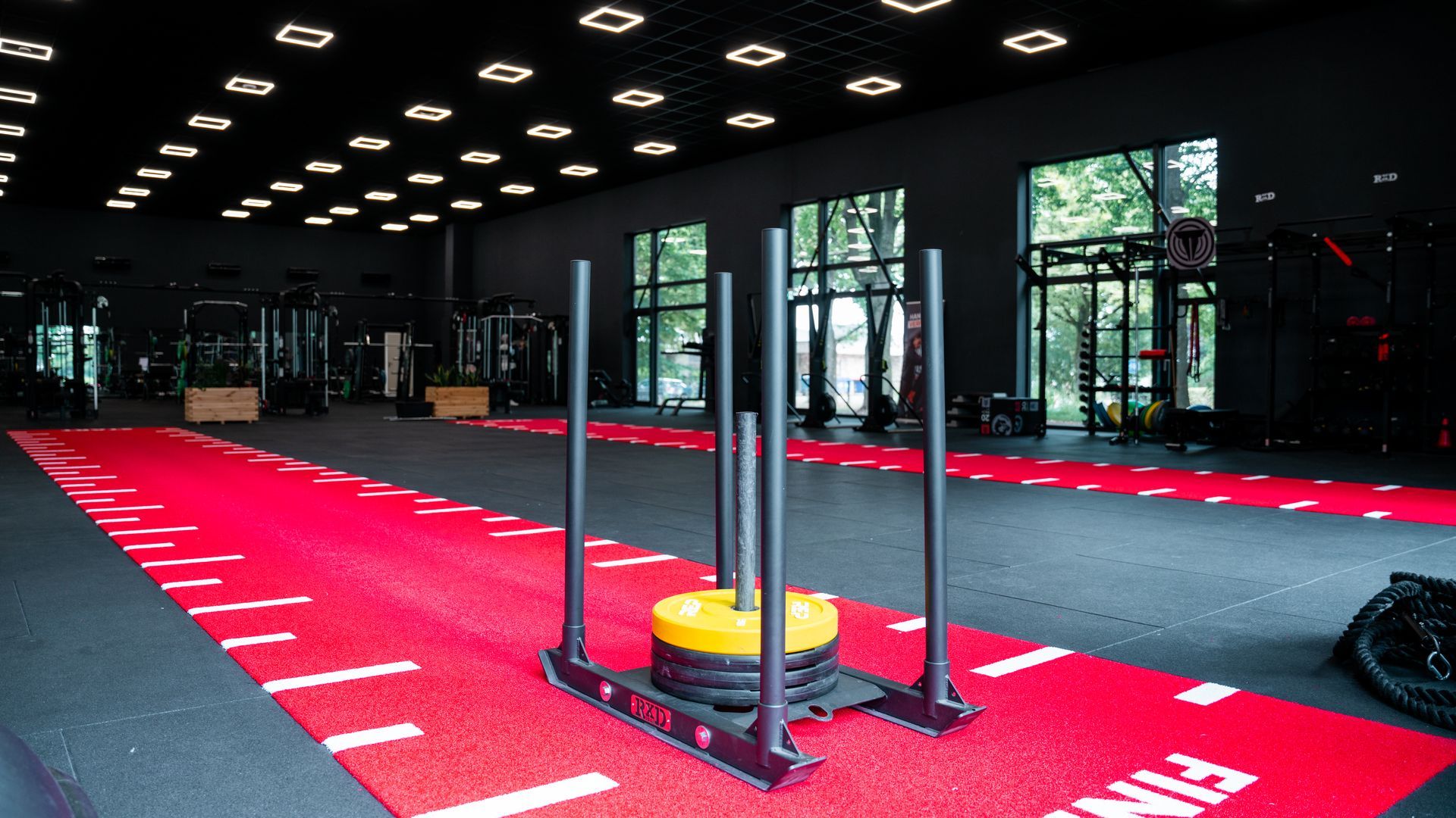 Mensen sporten binnen, met hoge knieën en rode matten op de vloer.