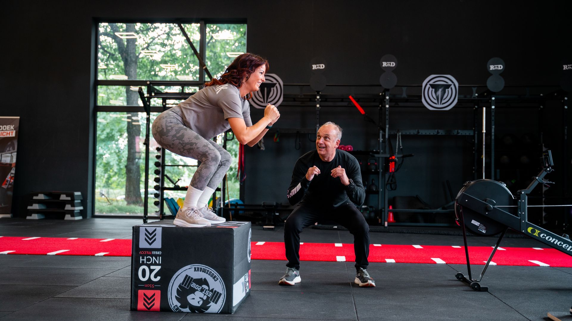 Twee vrouwen doen box squats in een sportschool; één met 