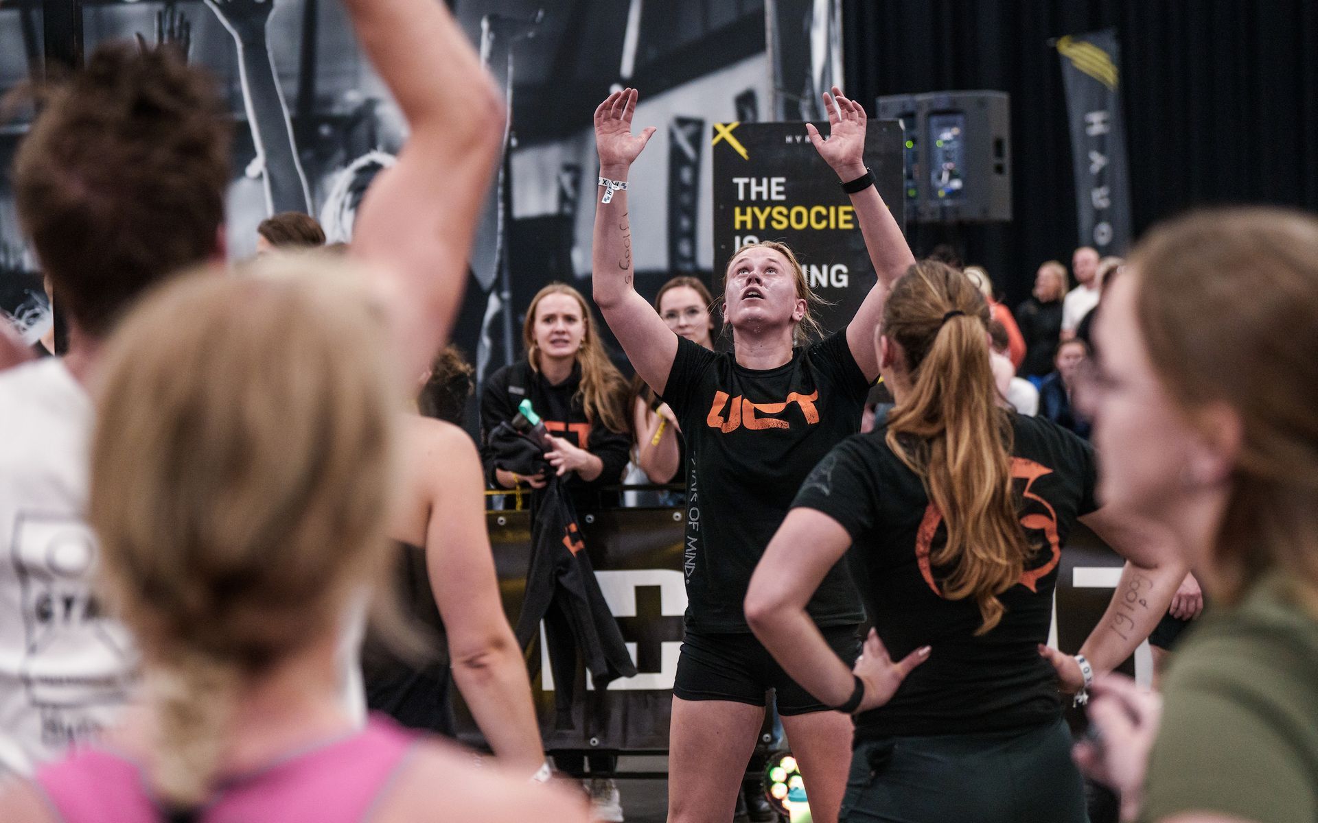 Vrouw in sportkleding zwaait met een kettlebell. Blond haar, geconcentreerde uitdrukking. Sportschoolomgeving.