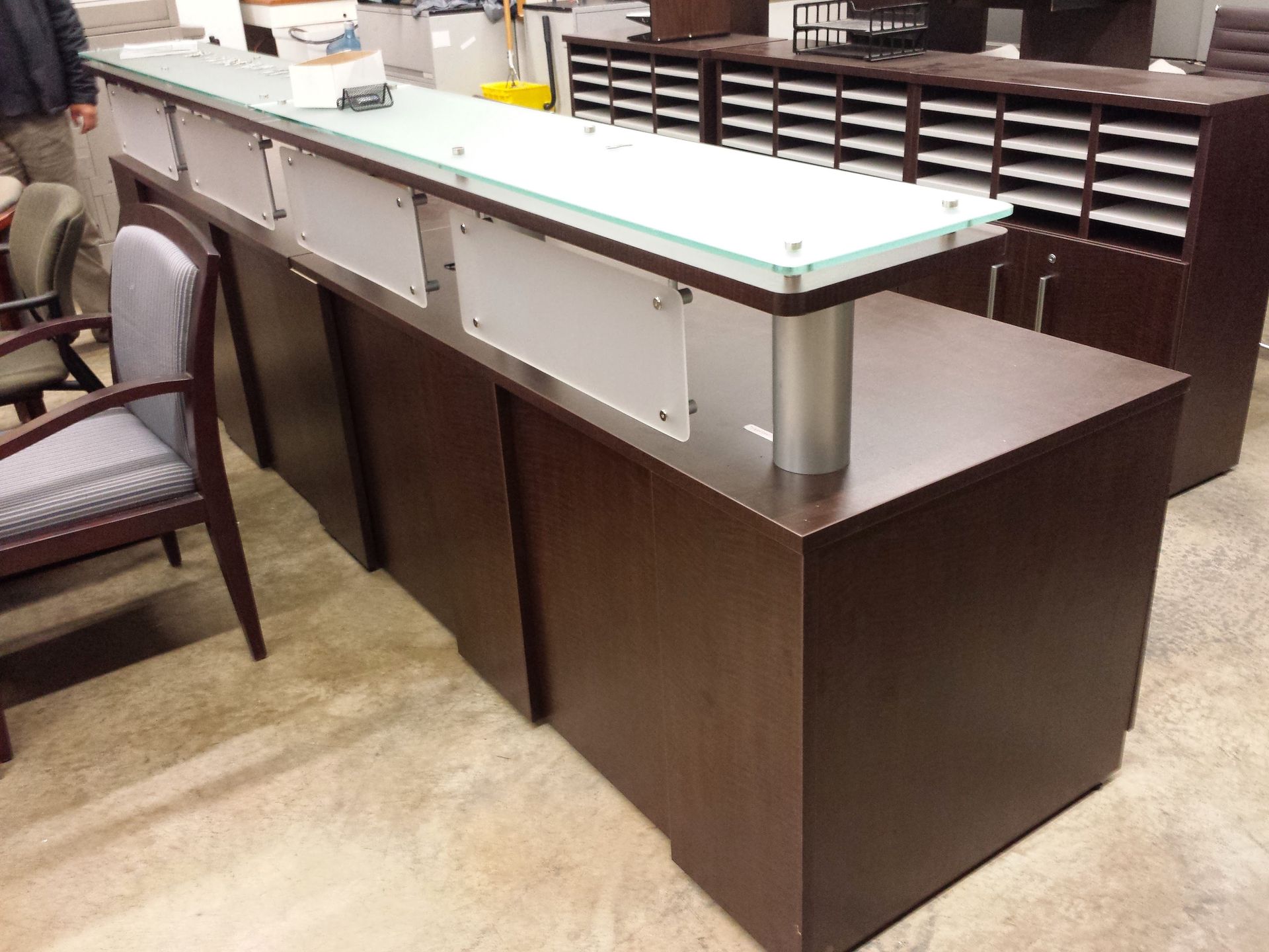 Dark wood reception desk with glass top and frosted panels.