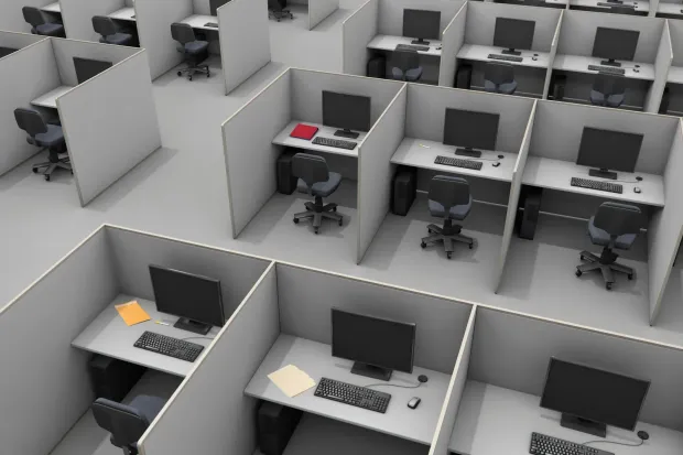 Office cubicle with tan and glass panels; desk and computer inside.