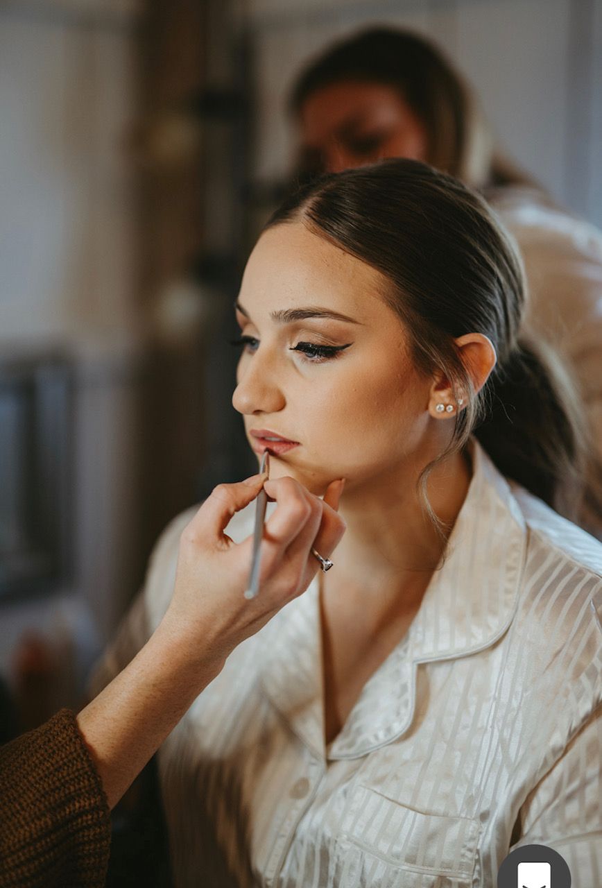 A woman is getting her makeup done by a makeup artist.