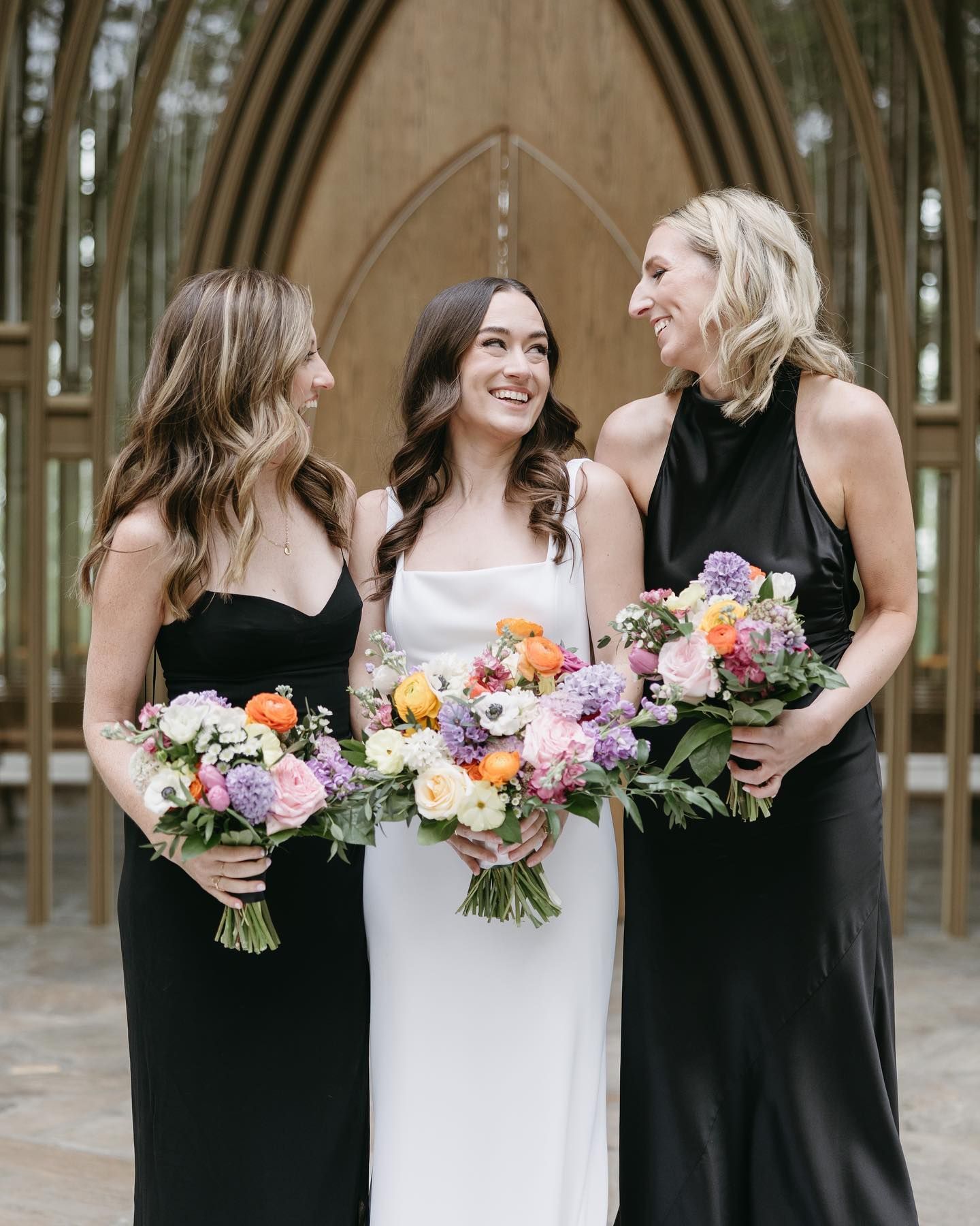 A bride and her bridesmaids are standing next to each other holding bouquets of flowers.