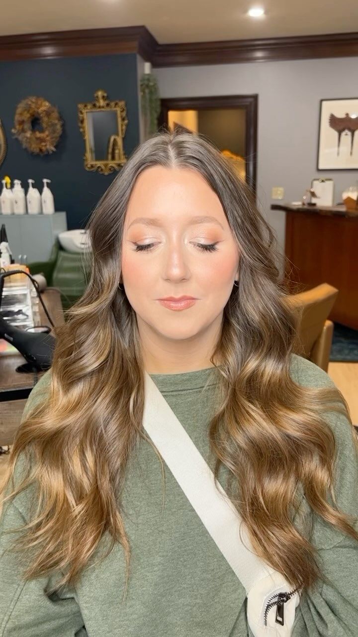 A woman with long brown hair is standing in a room with her eyes closed.