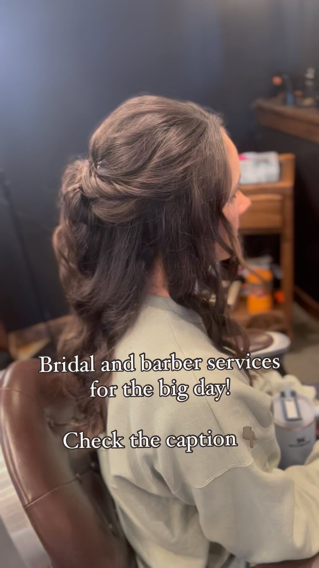 A woman is sitting in a chair with her hair in a half up half down hairstyle.