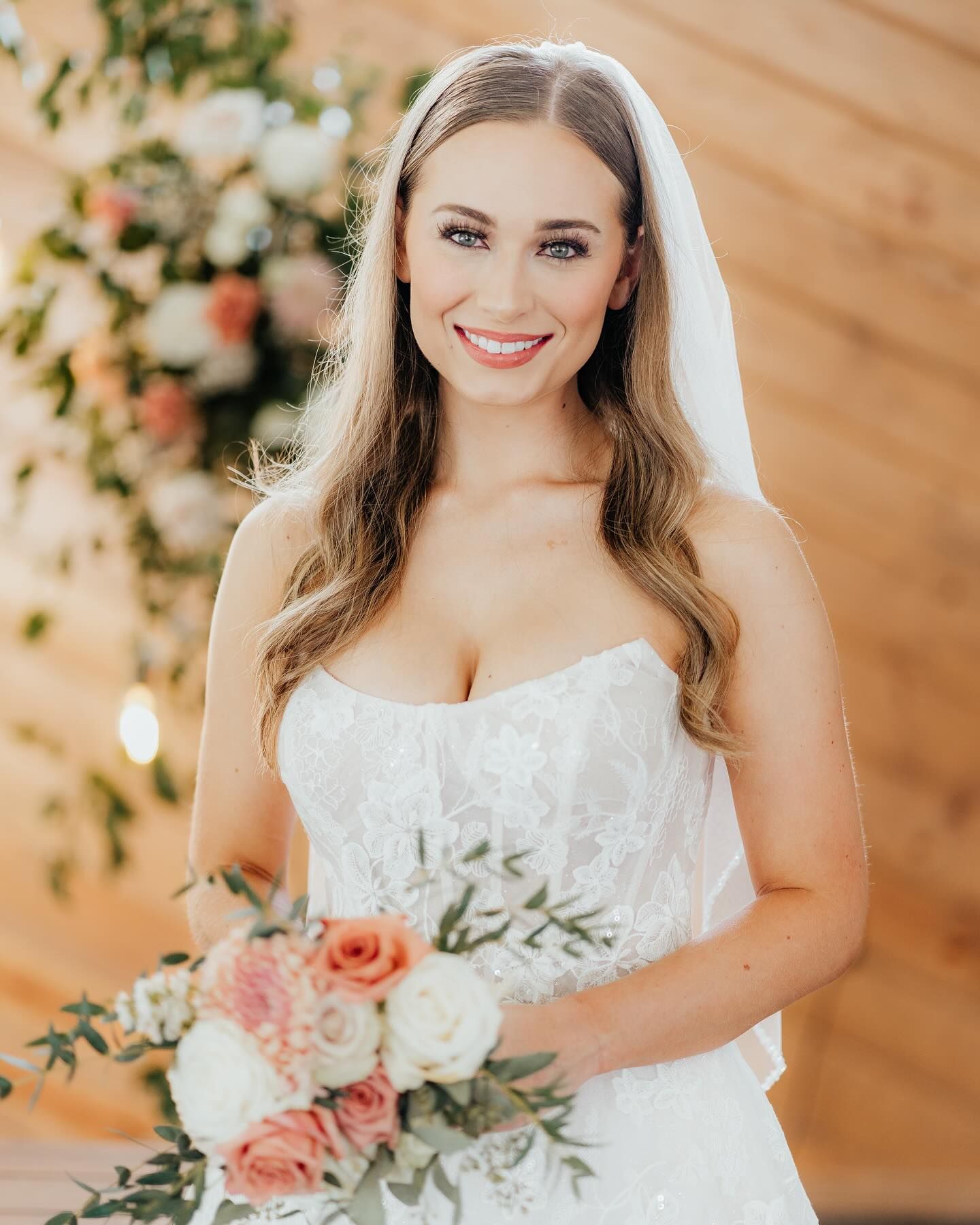 A bride in a white dress and veil is holding a bouquet of flowers.