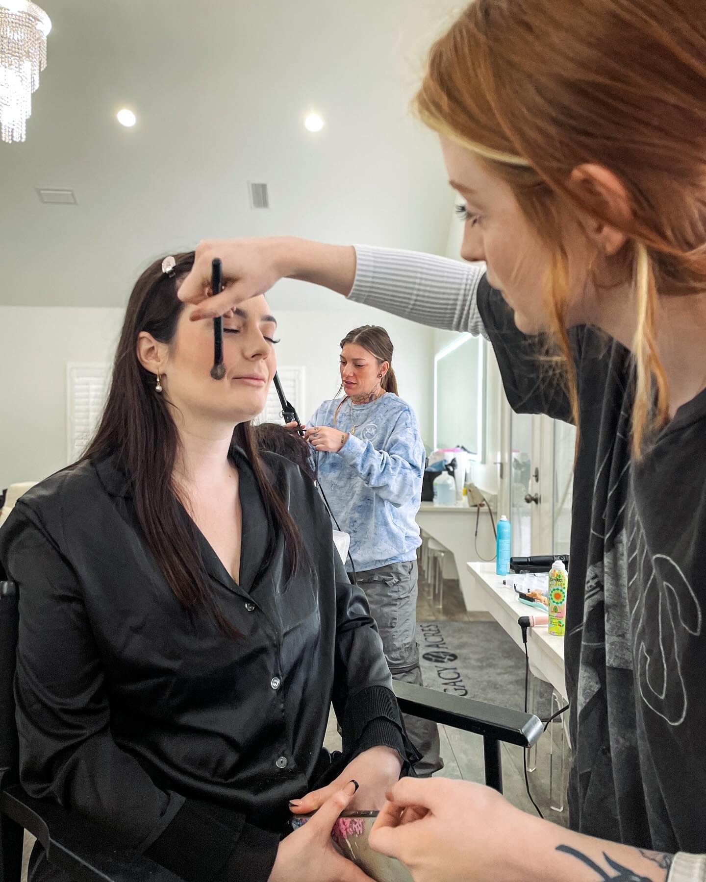A woman is getting her makeup done by a makeup artist in a salon.