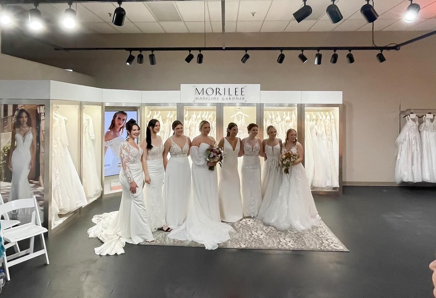 A group of women in wedding dresses are standing in a room.