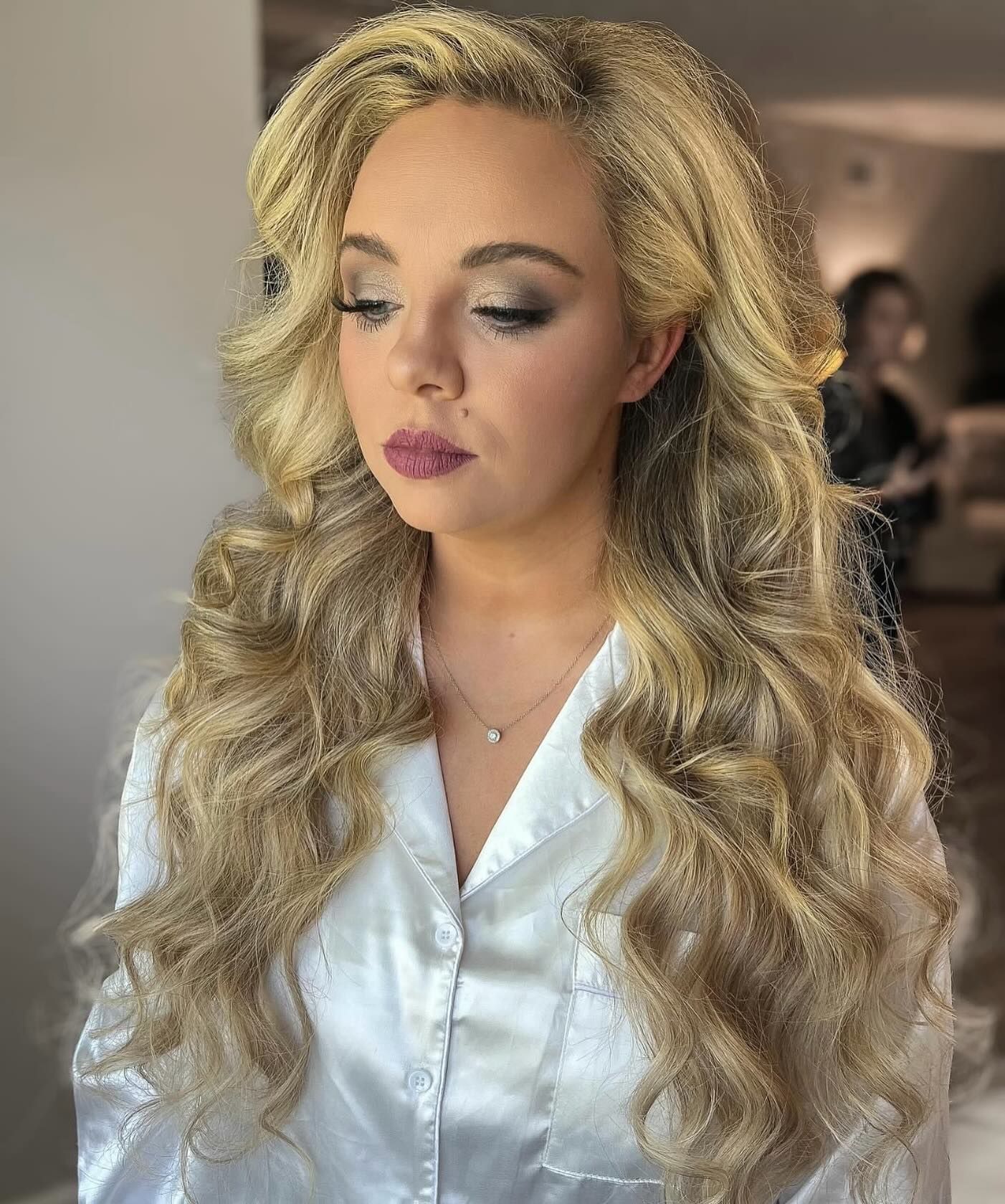 A woman with long blonde hair is wearing a white robe.