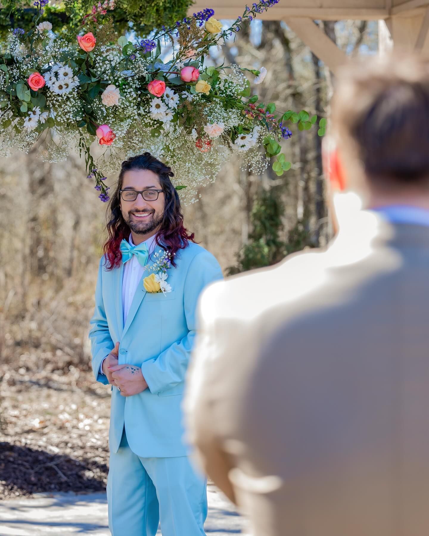 A man in a blue suit and bow tie is standing in front of a man in a suit.