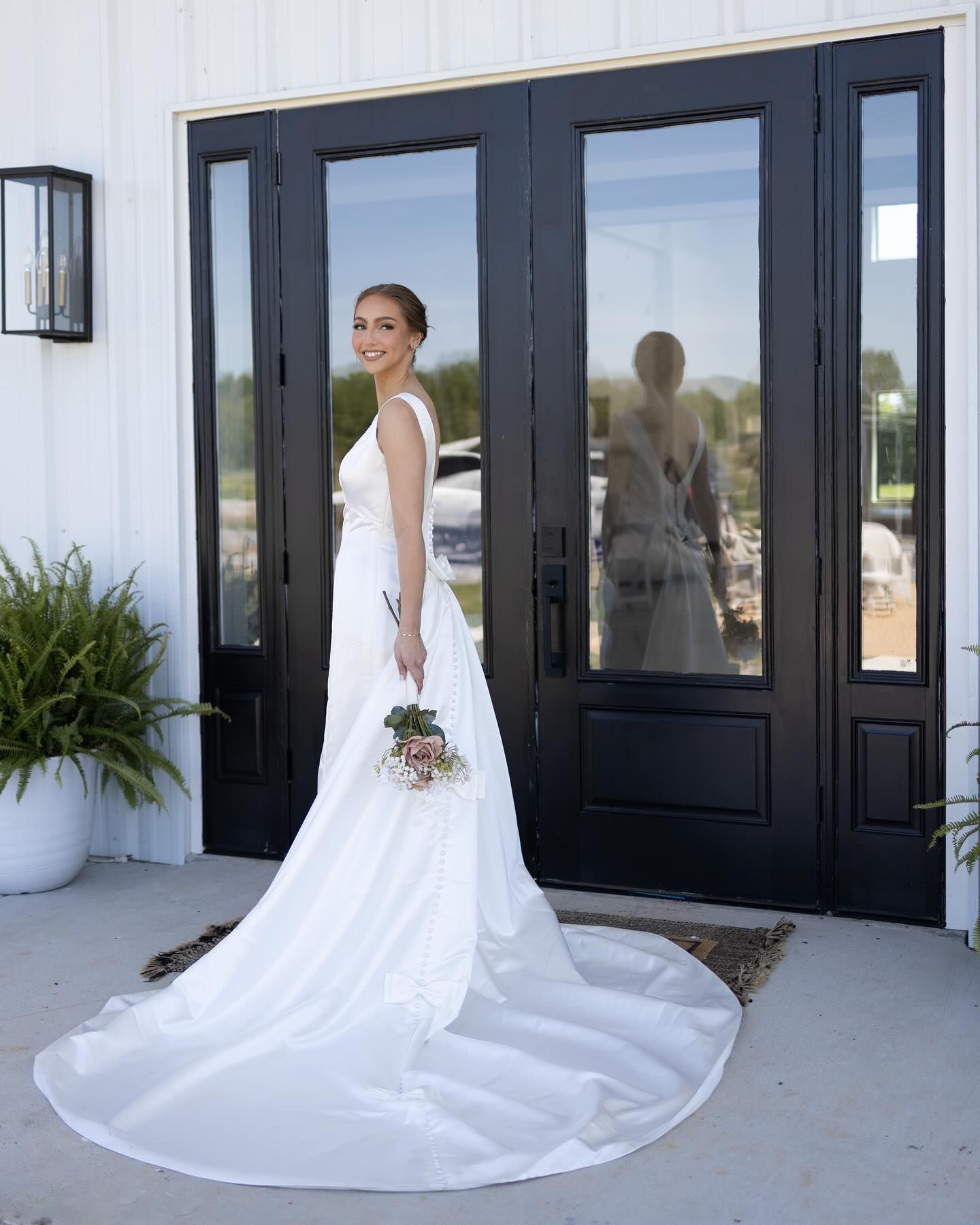 A bride in a wedding dress is standing in front of a black door.