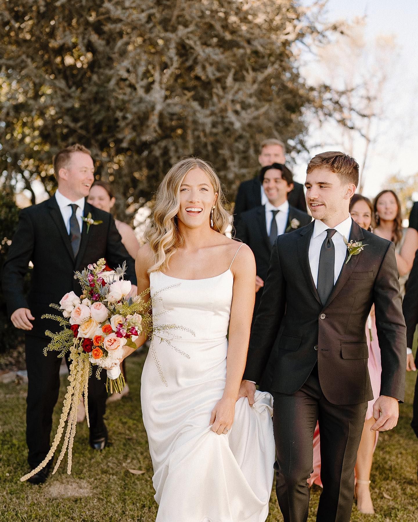 A bride and groom are walking with their wedding party.