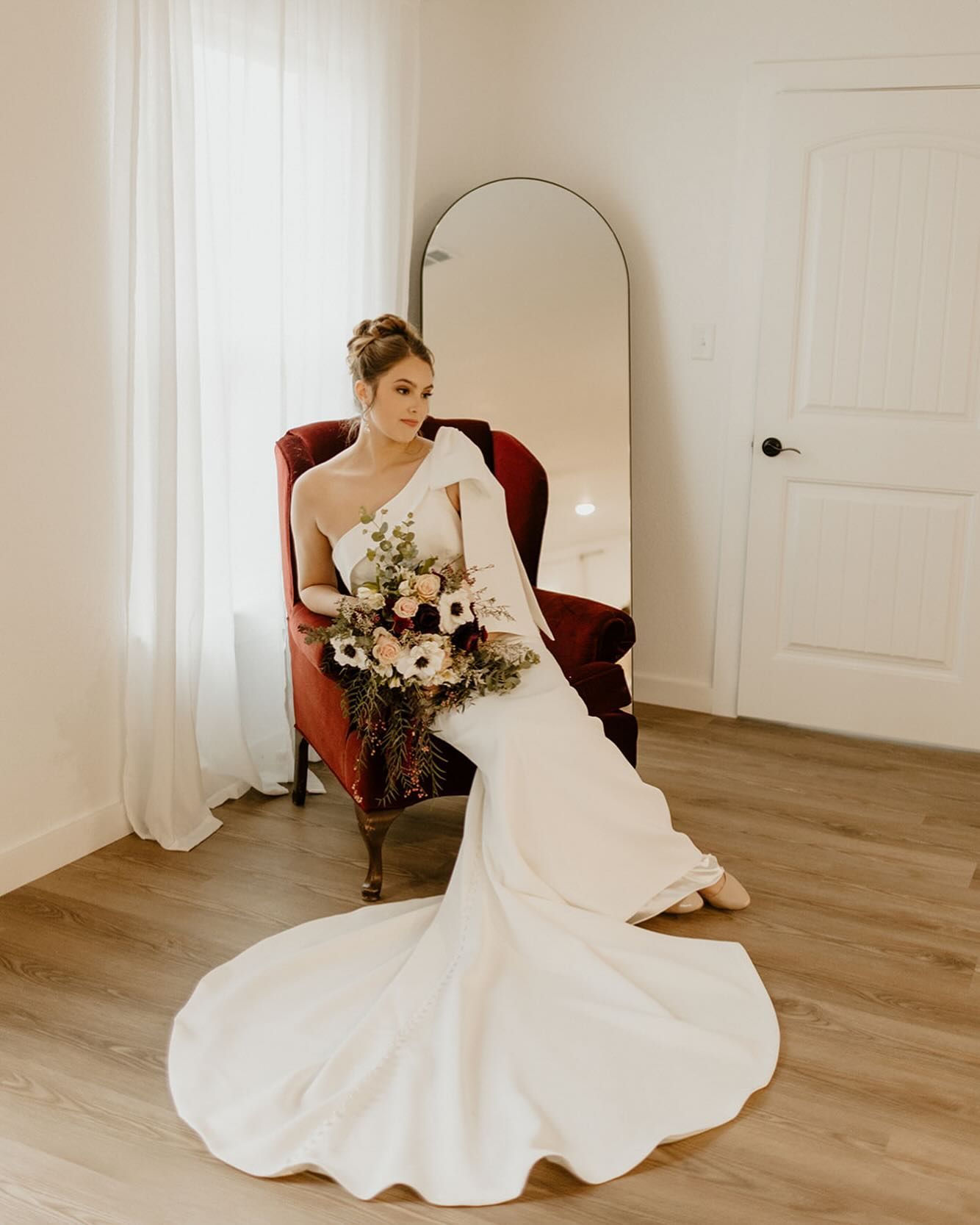 A bride in a wedding dress is sitting in a chair holding a bouquet of flowers.
