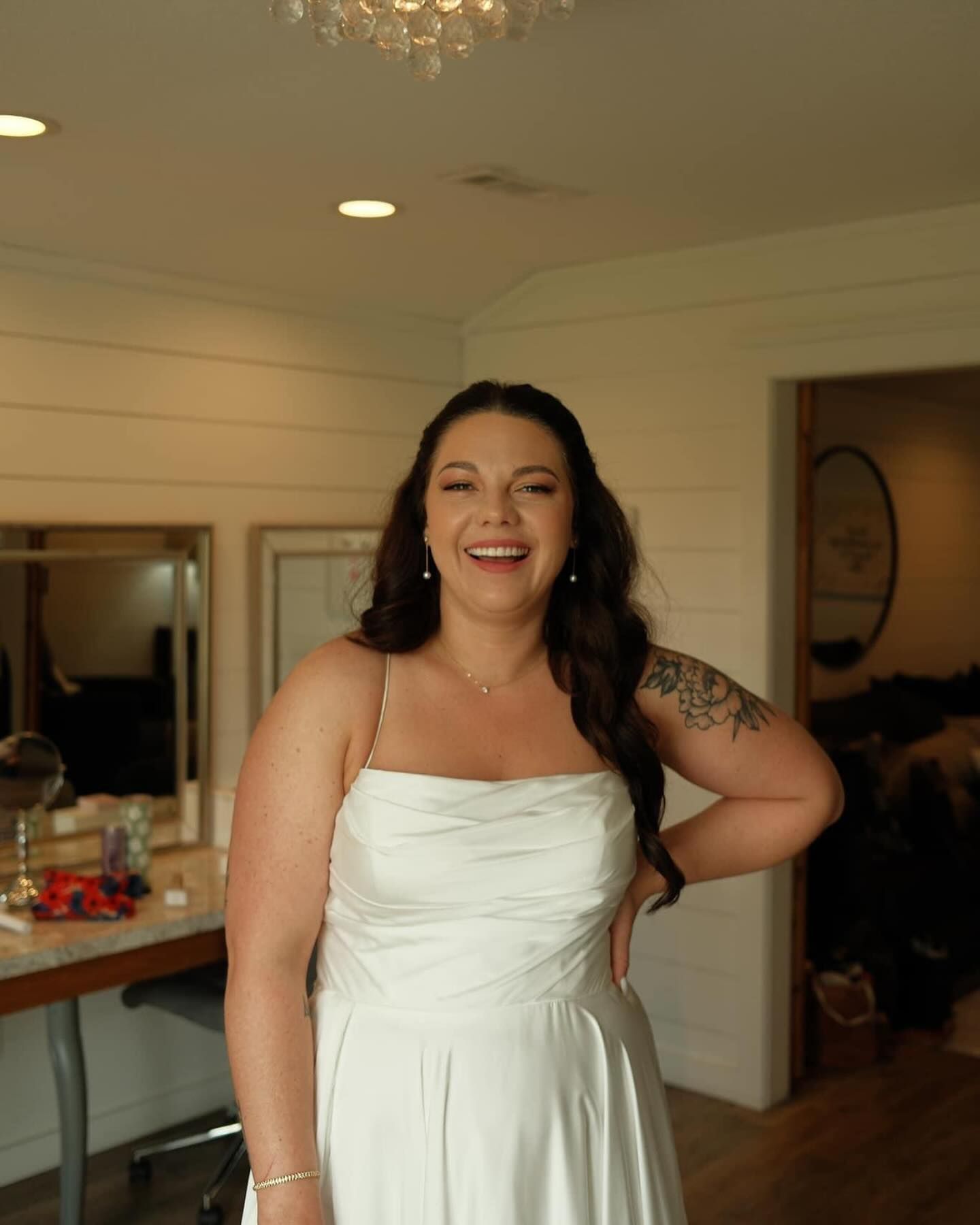 A woman in a white dress is smiling in a room.