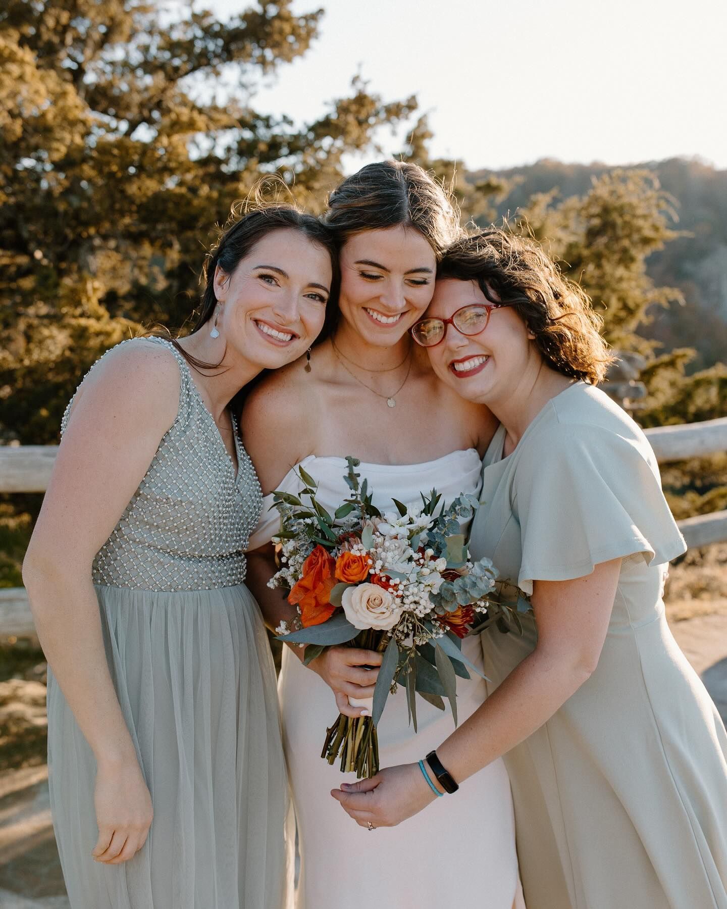 A bride and her two bridesmaids are posing for a picture.