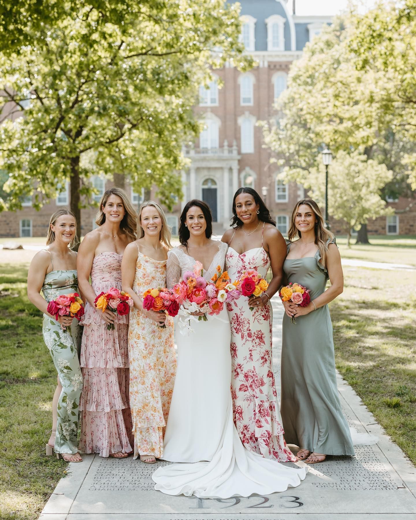 A bride and her bridesmaids are posing for a picture in front of a building.