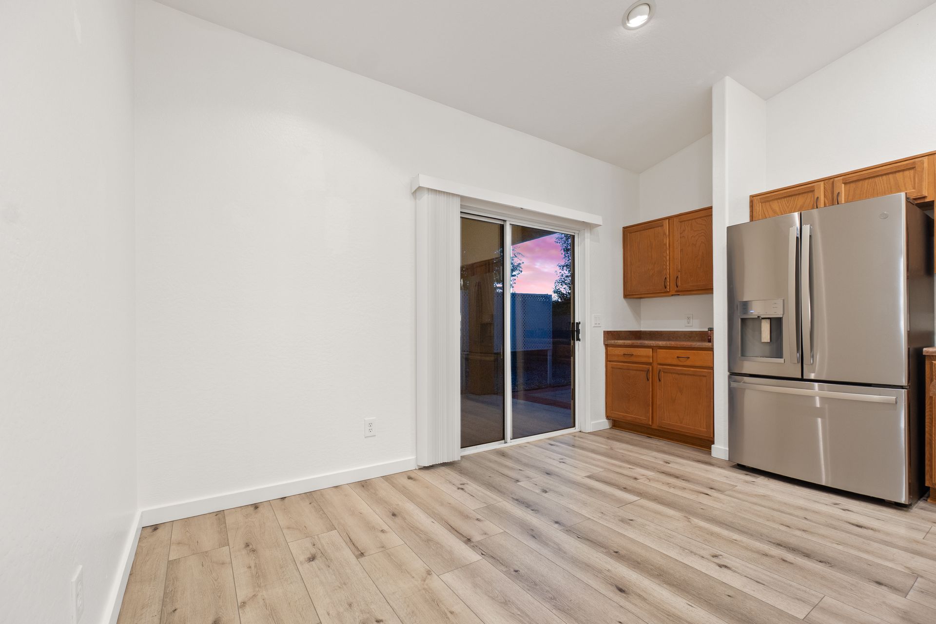 Kitchen with wood cabinets, stainless steel fridge, and sliding glass door to outside.