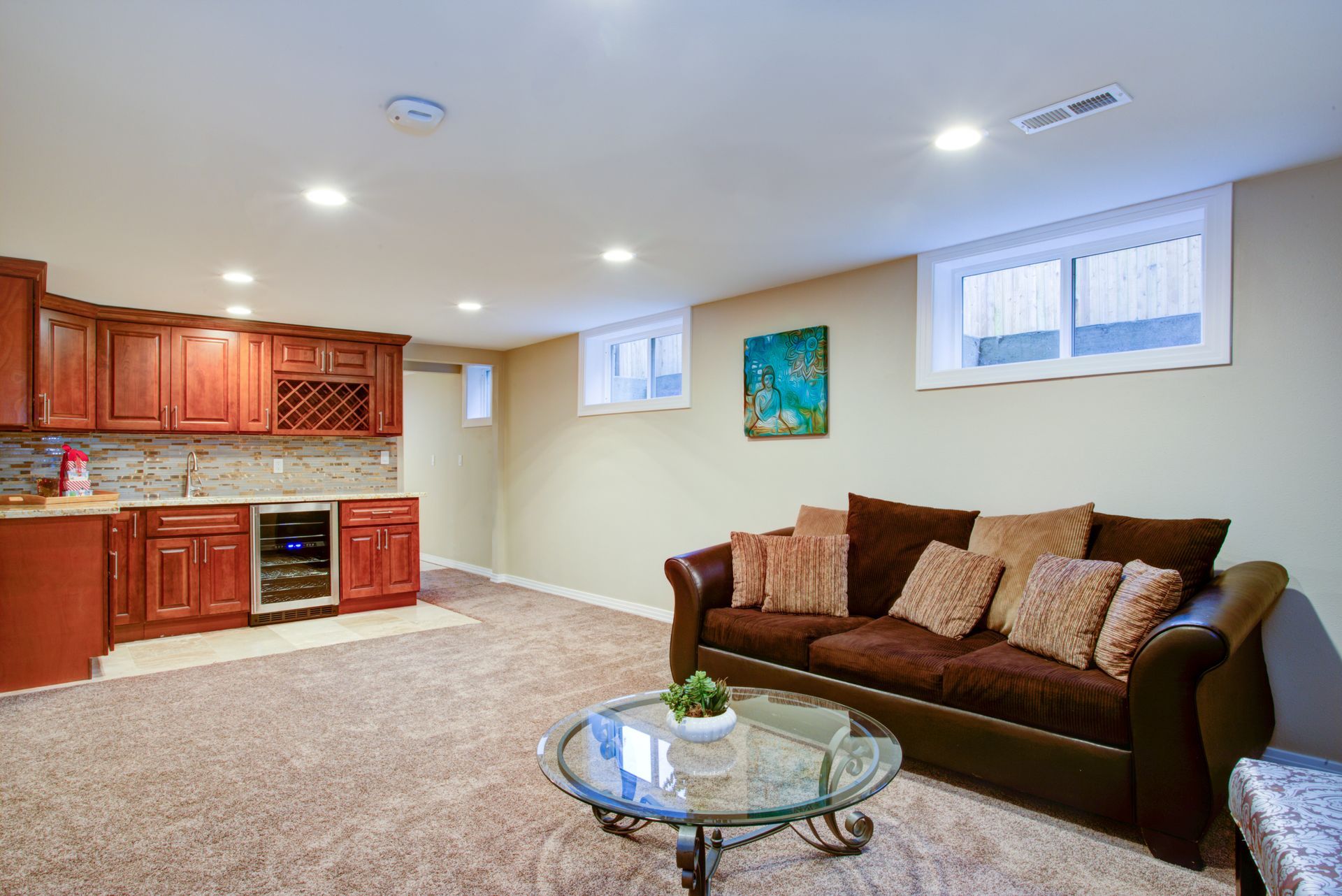 Living room with brown sofa, wet bar, windows, and light beige walls.