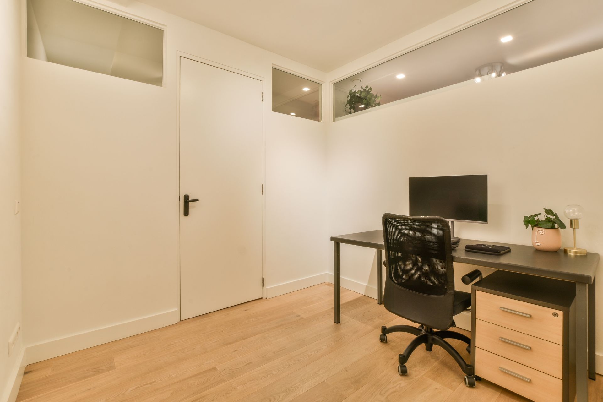 Home office with desk, chair, computer, and file cabinet. White walls, wood floor.