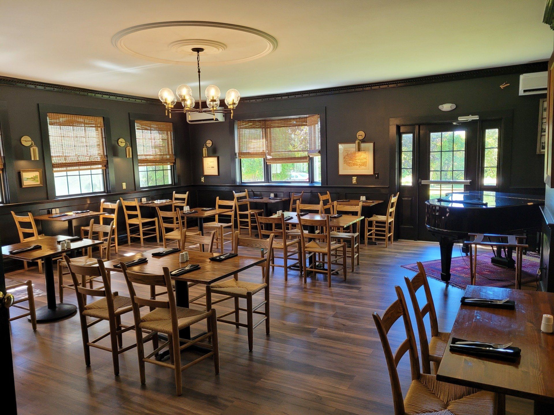 A large dining room with tables and chairs and a piano.