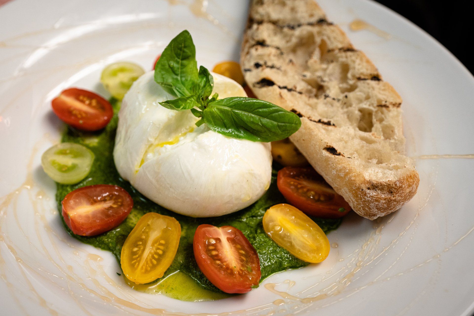 A white plate topped with tomatoes , mozzarella , basil and bread.