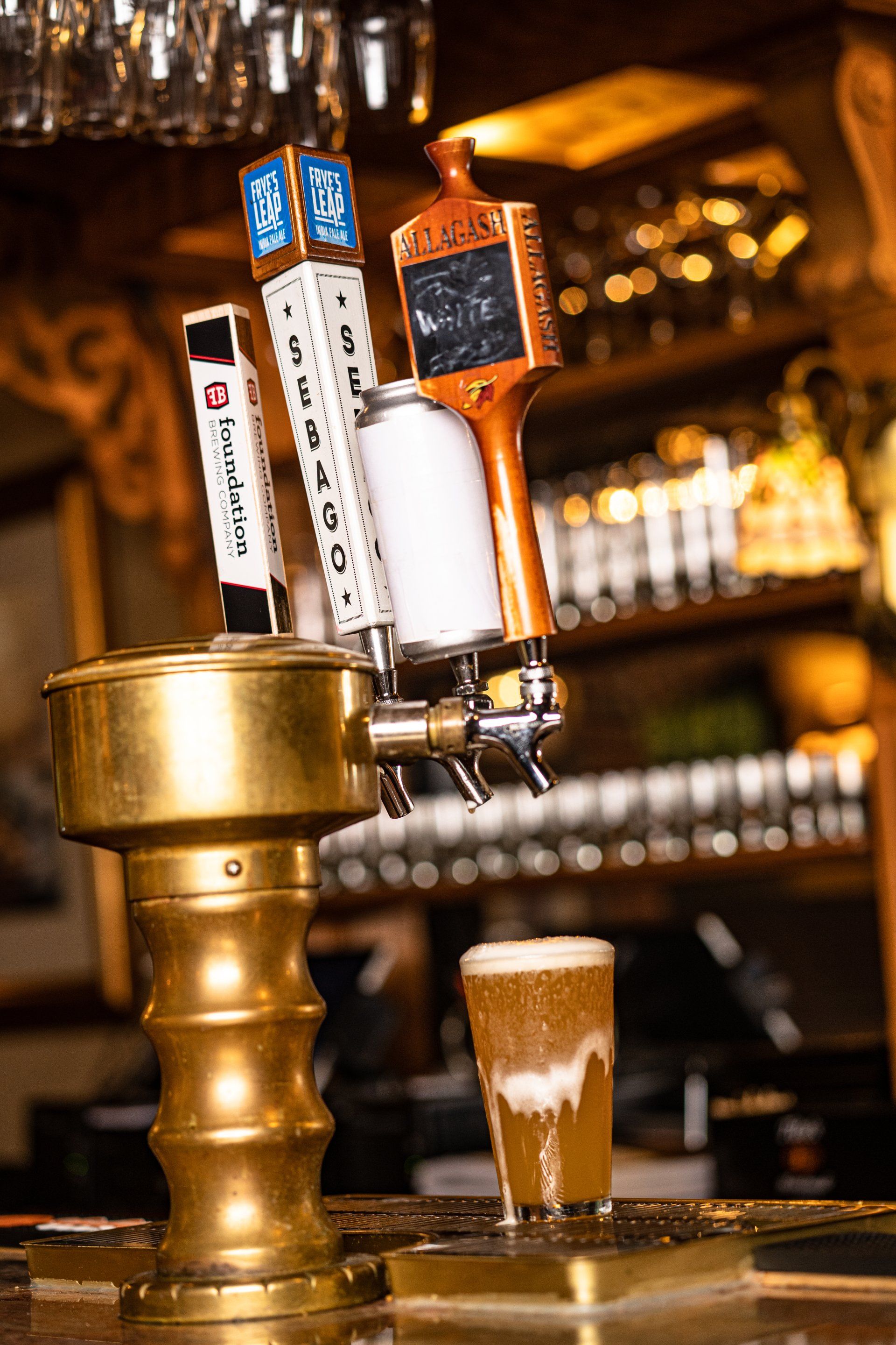 A bar with a beer tap and a glass of beer.